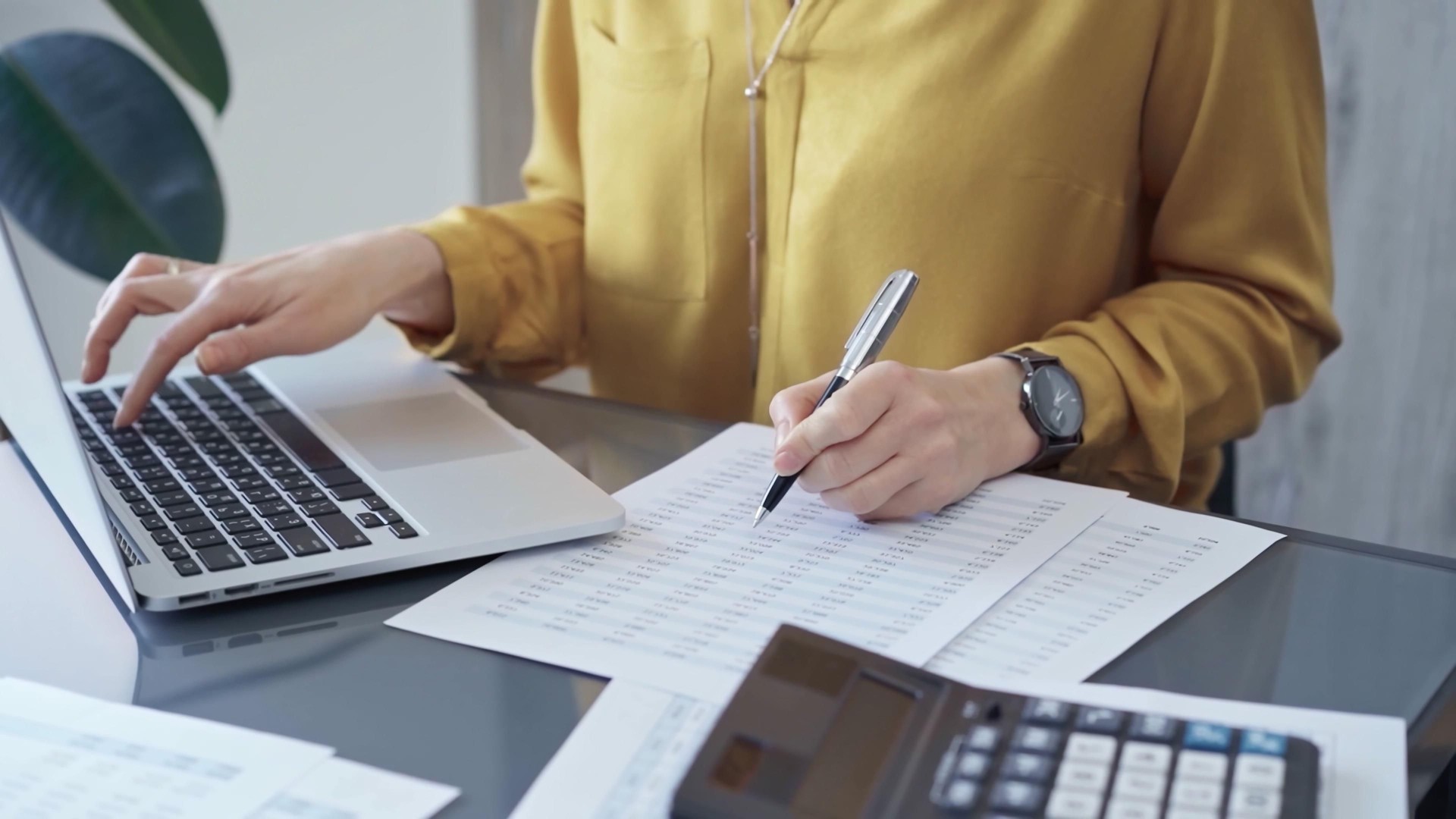 Professional business woman in yellow blouse is working on financial reports. Close-up of a woman's hands as she works on finance documents. Audit and taxes Professional business woman in yellow blouse is working on financial reports. Close-up of a woman's hands as she works on finance documents. Audit and taxes